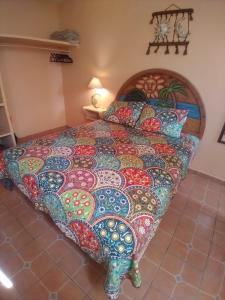 Una cama grande con una manta colorida. en La Casita de la Penita, en Peñita de Jaltemba