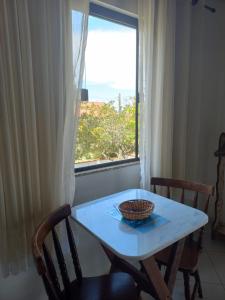 a table and chairs with a window and a bowl on it at Recanto das Acacias in Balneário Camboriú