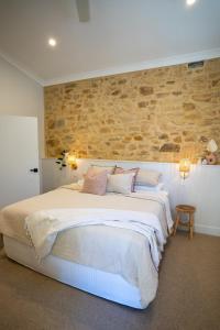 a bedroom with a large bed with a stone wall at Adelaide Hills Luxury Escape - 1884 Summertown in Summertown