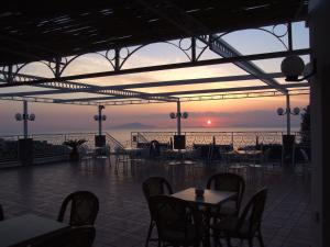 a restaurant with tables and chairs with a sunset in the background at Hotel Dania in Sorrento