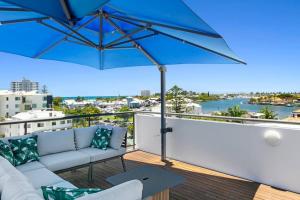a patio with a couch and an umbrella at Incredible Beachside Penthouse-RIVA11 in Mooloolaba