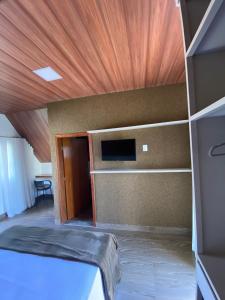 Cette chambre comprend un lit et un plafond en bois. dans l'établissement Chalezinho Pousada, à Brumadinho