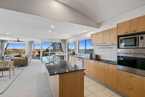 a large kitchen with a view of a living room at Incredible Beachside Penthouse-RIVA11 in Mooloolaba