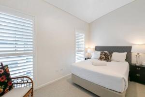 a white bedroom with a bed and a chair at Incredible Beachside Penthouse-RIVA11 in Mooloolaba