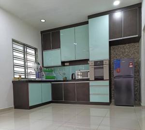 a kitchen with brown cabinets and a stainless steel refrigerator at Oro Homestay in Kluang