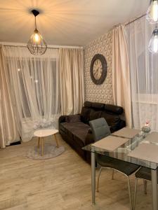 a living room with a couch and a clock on the wall at Uroczy Apartament z Patio in Szczecin