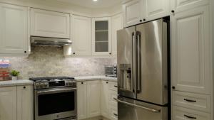 uma cozinha com armários brancos e um frigorífico de aço inoxidável em Le Boutique Great Toronto em Mississauga
