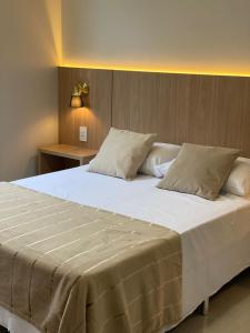 uma cama grande com lençóis brancos e almofadas em Apartamento Concierge Sensacional em Marabá