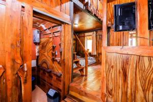 Elle comprend un salon avec des murs en bois et une télévision murale. dans l'établissement Rimbono Homestay, à Borobudur