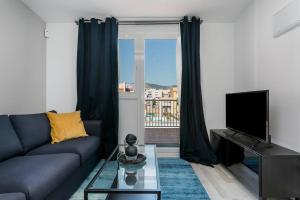ein Wohnzimmer mit einem blauen Sofa und einem TV in der Unterkunft Amazing Attic With Terrace in Hospitalet de Llobregat