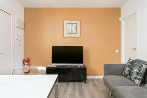 uma sala de estar com uma televisão de ecrã plano e um sofá em Cozy&new With Terrace em Hospitalet de Llobregat