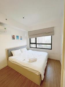 um quarto com uma grande cama branca e uma janela em HHomes - Cozy 2 Bedroom & Pool GYM at Masteri Thao Dien D2 em Ho Chi Minh