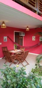 eine Terrasse mit einem Tisch und Stühlen vor einer roten Wand in der Unterkunft Imbassai - Casa Alto Padrão completa - Condominio Fechado - A2B1 in Imbassai