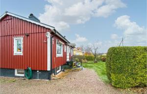 une maison rouge avec une haie à côté dans l'établissement Lovely Home In Laholm With Wifi, à Laholm