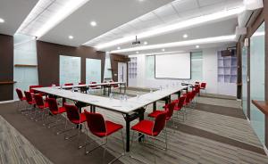 a conference room with a long table and red chairs at Berry Biz Hotel Sunset Road in Seminyak