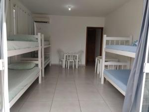 Habitación con literas, mesa y sillas. en Pousada Pontal Jurerê, en Florianópolis