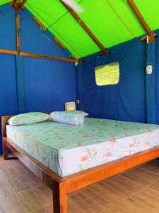 uma cama numa tenda com uma parede verde e azul em Beach Camp Lombok em Sekotong