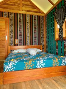 um quarto com uma cama de madeira com lençóis azuis em Beach Camp Lombok em Sekotong