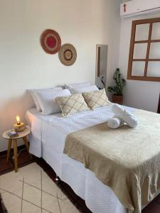 Un dormitorio con una cama blanca con una vela. en Melasti Marine House - Casa em Condomínio Familiar com Piscina na Marina de Búzios e Wifi 1G, en Búzios