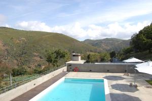 a swimming pool on top of a house with a mountain at Quinta dos Castanheiros - Turismo Rural in Negreda