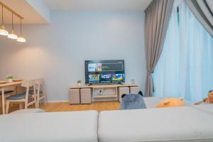 sala de estar con sofá blanco y TV en Ipoh Tambun Lost World Sunway Onsen Suites Luna 2R2B 8paxs, en Ipoh
