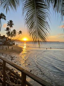 a sunset on a beach with a palm tree at Villa da Praia in Pipa
