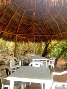 ein Picknicktisch und Stühle unter einem Strohdach in der Unterkunft Manglar Pacific in Los Ayala