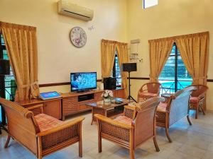 sala de estar con sillas y TV en Yussy Homestay at Afamosa Villa, en Kampong Alor Gajah