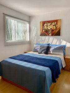 um quarto com uma cama com lençóis azuis e um quadro em 3 Quartos Melhor Valor do Df próximo ao Aeroporto e Plano em Brasília