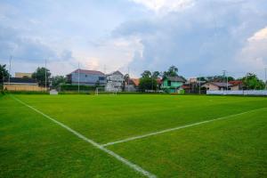 ジョグジャカルタにあるUrbanview Griya Kusumo Seturan Yogyakartaの背景に家々が見える緑のサッカー場