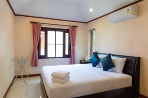 um quarto com uma grande cama branca com almofadas azuis em The New Villa em Chaweng