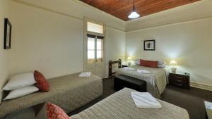 ein Hotelzimmer mit 2 Betten und einem Tisch in der Unterkunft Commercial Travellers House in Gulgong