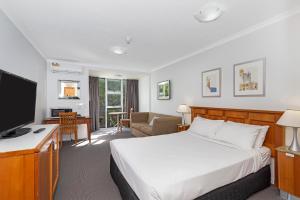 um quarto de hotel com uma cama e uma televisão em Airport Heritage Motel em Brisbane