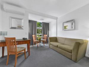 sala de estar con sofá, mesa y sillas en Airport Heritage Motel, en Brisbane