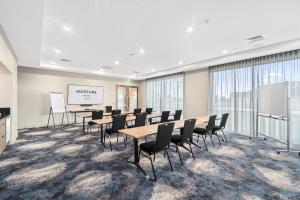 een vergaderzaal met tafels en stoelen en een whiteboard bij Mercure Pakenham in Pakenham