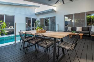 einen Esstisch aus Holz und Stühle auf einer Terrasse in der Unterkunft Pembroke House - Inner city luxury in Cairns