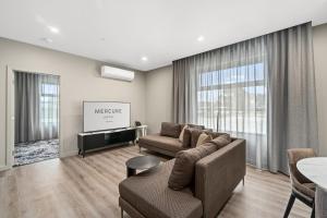 a living room with a couch and a tv at Mercure Pakenham in Pakenham