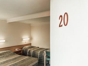 una habitación de hotel con 2 camas con el número en la pared en Downtown Motel Warrnambool, en Warrnambool