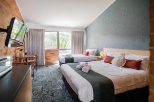 Bribie Island Hotel في Bellara: غرفة فندقية بسريرين وتلفزيون بشاشة مسطحة