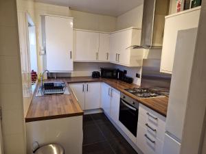 a kitchen with white cabinets and wooden counter tops at Chester le Street's Diamond; 3 Bedroom House in Chester-le-Street +28 photos
