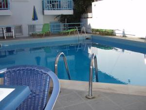 a swimming pool with two chairs and a table and a table and chairs at Renia Studios in Agia Pelagia