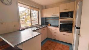 una pequeña cocina con armarios blancos y una ventana en K Resort Surfers Paradise Apartments, en Gold Coast