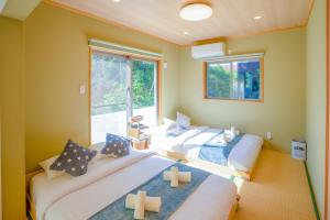 恩納村にある#3LDK一軒家 #長期滞在可能 #海まで4分-- Starry Sky Resort Okinawa --の大きな窓2つが備わる客室で、ベッド2台が備わります。