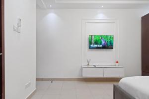 a white bedroom with a tv on a white wall at Luxury 3 Bedroom Apartment In Lekki Phase1 in Lekki