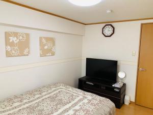 een slaapkamer met een bed en een flatscreen-tv bij K&M Heights - Vacation STAY 32223v in Tokyo