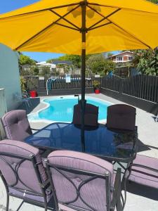 una mesa con una sombrilla amarilla junto a una piscina en Rosetown Motel en Te Awamutu