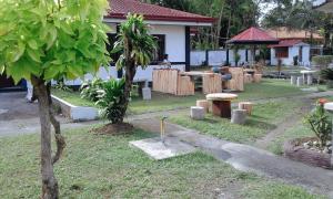a garden with trees and tables and a person in a house at RedDoorz @ Golden Travellers Inn Antique in Hamtic
