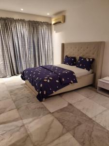 a bedroom with a bed with a blue comforter and a window at Luxury 3 Bedroom with Pool and Gym In Oniru Victoria Island Lagos in Lagos