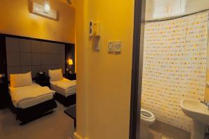 Khorfakkan Hotel Apartments في خور فكان: غرفة فندقية بسريرين ومغسلة