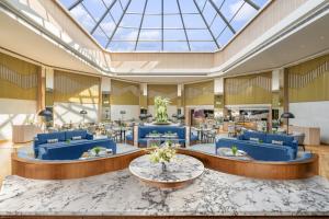 a lobby with blue chairs and tables and a glass ceiling at Vivanta Meghalaya Shillong in Shillong